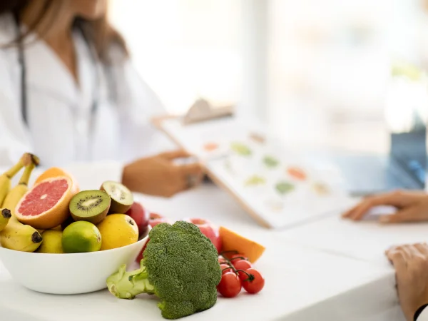 Dottoressa nutrizionista mostra un piano alimentare accanto a frutta e verdura